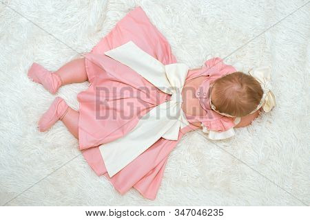 A Little Girl In A Beautiful Dress Is Lying On A Blanket