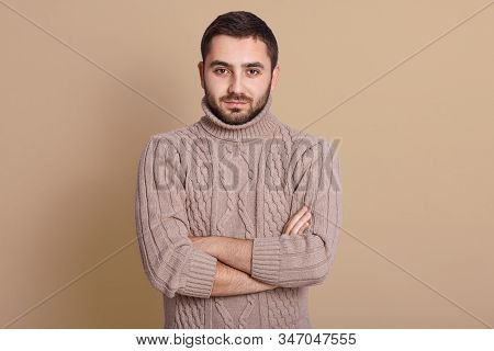 Close Up Portrait Of Smiling Man Standing With Arms Crossed Against Beige Background, Looking At Cam