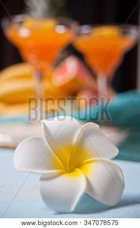 Plumeria Frangipani Flower And Glasses Of Tropical Exotic Multifruit Juice Cocktail Drink On The Bac