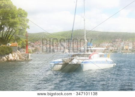 Sailing Catamaran Sails Along The Rocky Green Coast Past The Red Literary Sign - The Fairway Lightho