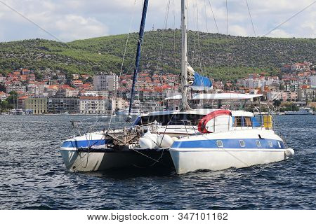 Sailing Catamaran Sails Along The Rocky Green Coast Past The Red Literary Sign - The Fairway Lightho