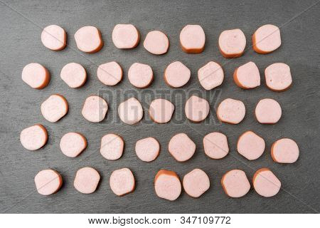 Put In Row Many Pieces Of Fresh Pork Sausages Of Different Sizes On Stone Board, Cut For Frying And 