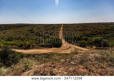 T-junction Of Dirt Roads In The Middle Of A Wide Green Steppe, Between Low Bushes