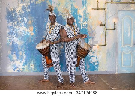A Group Of People In Traditional African Costumes Playing Jembe Drums