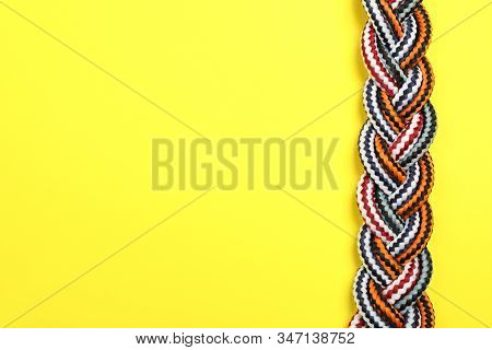 Top View Of Braided Colorful Ropes On Yellow Background, Space For Text. Unity Concept