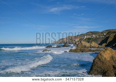 Large Ocean Waves Crash Against Coastal Stones On A Clear Sunny Day On The European Coast. Winter Ho