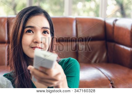 Close-up Of Asian Woman Is Turn-on/off Air Conditioner Split Type By Remote Controller In Living Roo