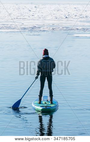Silhouette Of Unrecognizable Woman In Wetsuit Paddling On A Sup Board. Female Floating On A Stand Up