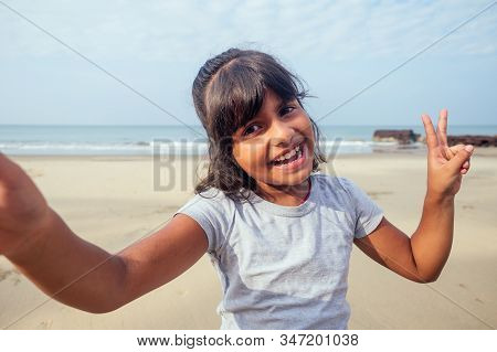 Cute Girl 7 Or 8 Years Old Asian American Mixed Enjoying Holidays Taking Selfie In Goa And Soving V-