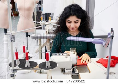 Dressmaker Using Professional Overlock Sewing Machine In Workshop Studio. Equipment For Edging, Hemm