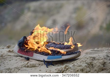 Burning Sports Sneakers Or Gym Shoes On Fire Stand On Sandy Beach Coast. Athlete Burned Out. Physica