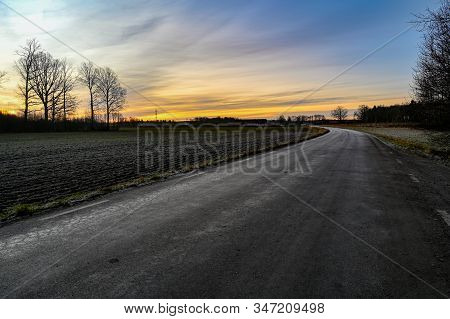 Curved Road Through Field With Orange Sunrise