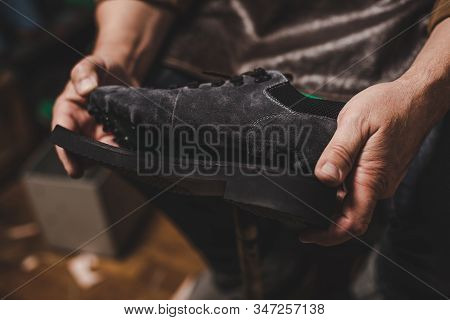 Cropped View Of Cobbler Holding Suede Shoe With Unfixed Sole In Workshop