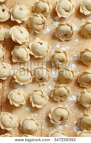 Raw Meat Pelmeni, Ravioli, Dumplings Top View On A Wooden Board