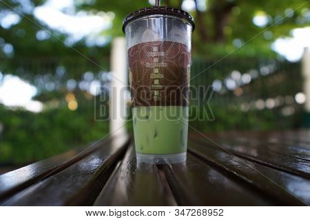 Close Up Image Of Milk Green Tea With Plastic Takeaway Glass On The Wood Table Bokeh Background