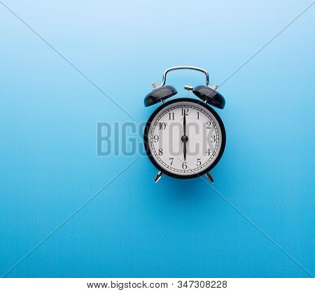 Alarm Clock On Blue Background Top View. Six O'clock.