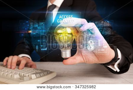 Businessman holding lightbulb with ACCESS GRANTED inscription, online security idea concept