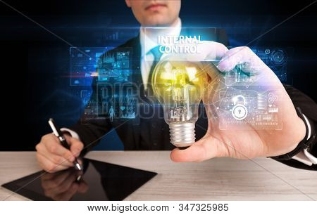 Businessman holding lightbulb with INTERNAL CONTROL inscription, online security idea concept