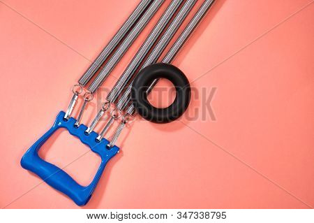 Espander Spring With Blue Handle On Pink Background