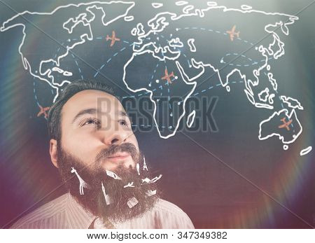 Portrait Of Brooding Bearded Man Against A Background Of A Chalk Board With World Map And Planes.