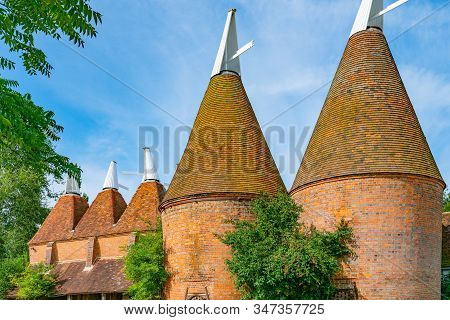 Oast Houses In Group Constructed Orange Brick And Tile With White Cowls On Top In South Of England.