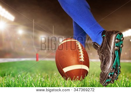 American Football Player Prepares To Kick Ball For Conversion Points Or Field Goal In Brightly Lit O
