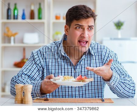 Young husband eating tasteless food at home for lunch