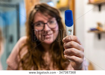 A Selective Focus Portrait View Of A Happy Caucasian Woman Holding A Pregnancy Test Kit With Positiv