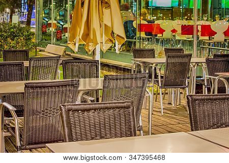 Wicker Chairs In One Of The Caffees Of Porto City In Portugal At Dusk.horizontal Image Orientation