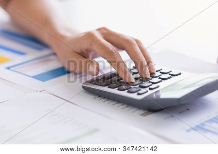 Businesswoman Using A Calculator To Calculate The Numbers Discussing The Charts And Graphs On Tablel