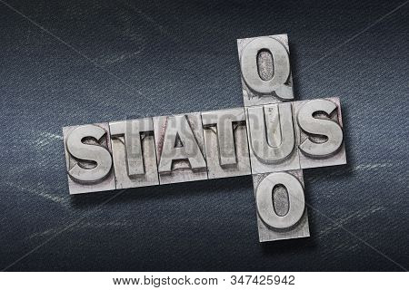 Status Quo Crossed Phrase Made From Metallic Letterpress On Dark Jeans Background
