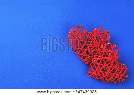 Two Beautiful Wicker Red Hearts On The Cornflowerblue Background. St Valentines Concept With Copy Sp