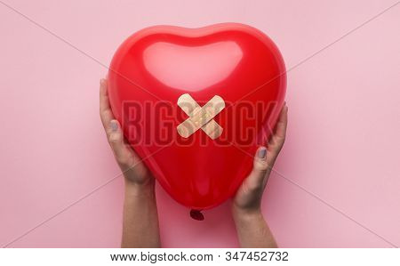 First Aid Band Plaster Strip Medical Patch Glued On Red Heart Balloon In Woman Hands On Pink Backgro