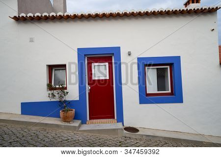 Cobblestone Street With Blue And White Traditional Colorful Homes And Buildings In The Algarve Town 