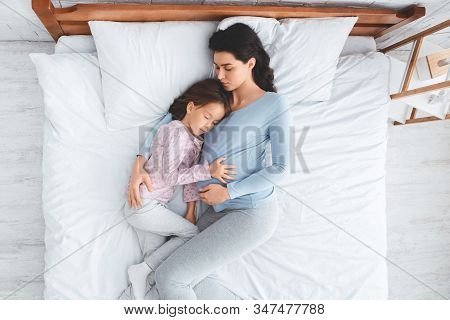 Peaceful Image Of Expecting Young Woman Having Nap With Little Daughter At Home, Top View