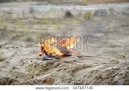 Burning Sports Sneakers Or Gym Shoes On Fire Stand On Sandy Beach Coast. Athlete Burned Out. Physica