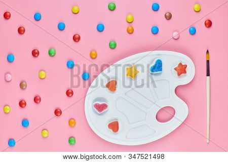 Art Of Sweetmeats Concept. Sweet Candy In Paint Palette On Pink Background. Love To Colorful Sweetme