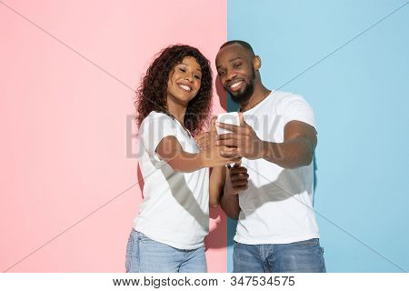 Taking Selfie. Young Emotional Man And Woman In Casual Clothes On Pink And Blue Bicolored Background