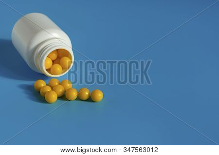 Yellow Vitamins Pour Out From A Pill Bubble On A Blue Background. Vitamin Complex. Multivitamins To 