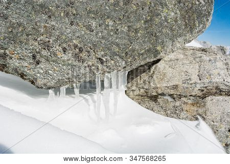 Ice Candles Formed On Granite Rock In The Mountains.