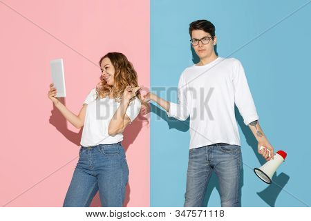 Shes Taking Selfie, Hes Trying To Pay Attention. Young And Happy Man And Woman On Pink, Blue Backgro