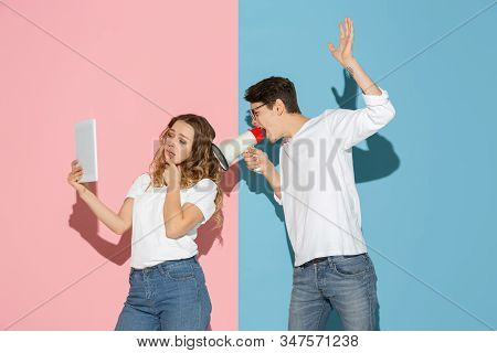Shes Taking Selfie, Hes Trying To Pay Attention. Young And Happy Man And Woman On Pink, Blue Backgro