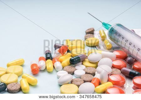 Medicine Pills And Disposable Syringe Closeup On Blue Background. Health Pharmacy Pharmacology Conce