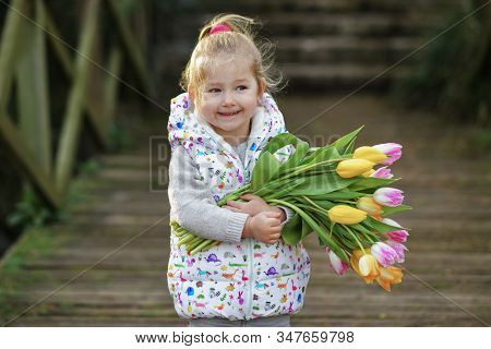 Portrait Of A Blonde Girl With A Bouquet Of Tulips In Her Hands