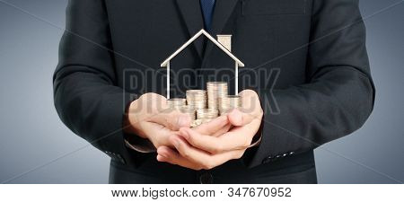 Growing Coins House On Stack Coins In Hand. Concept Of Investment Propert