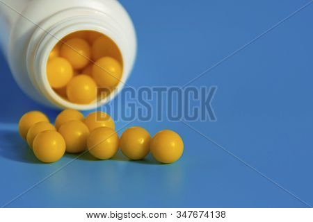 Yellow Vitamins Pour Out From A Pill Bubble On A Blue Background. Vitamin Complex. Multivitamins To 