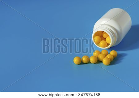 Yellow Vitamins Pour Out From A Pill Bubble On A Blue Background. Vitamin Complex. Multivitamins To 