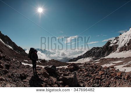Man Standing On The Rocky Path Around The Snow Remnants Under The Sun In Clear Sky