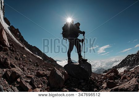 Man Standing On The Rock Around The Snow Remnants Under The Sun In Clear Sky
