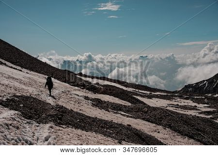 Man Walking On The Dirty Snow Path Looking Down Climbing On The Mountain